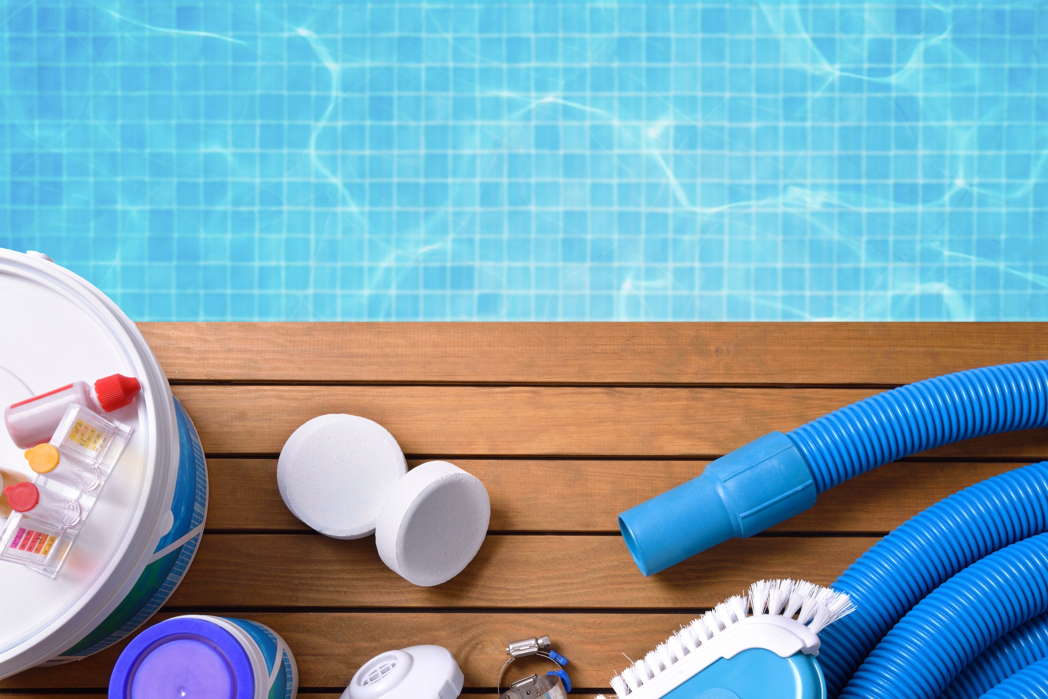 Pool cleaning supplies beside clear blue pool water